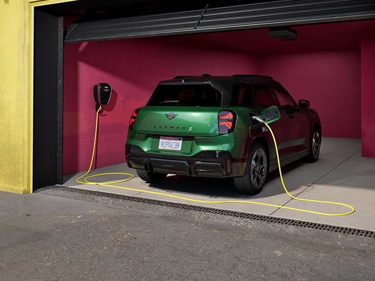 Πίσω όψη του αμιγώς ηλεκτρικού MINI Aceman σε χρώμα British Racing Green να φορτίζει σε γκαράζ. 