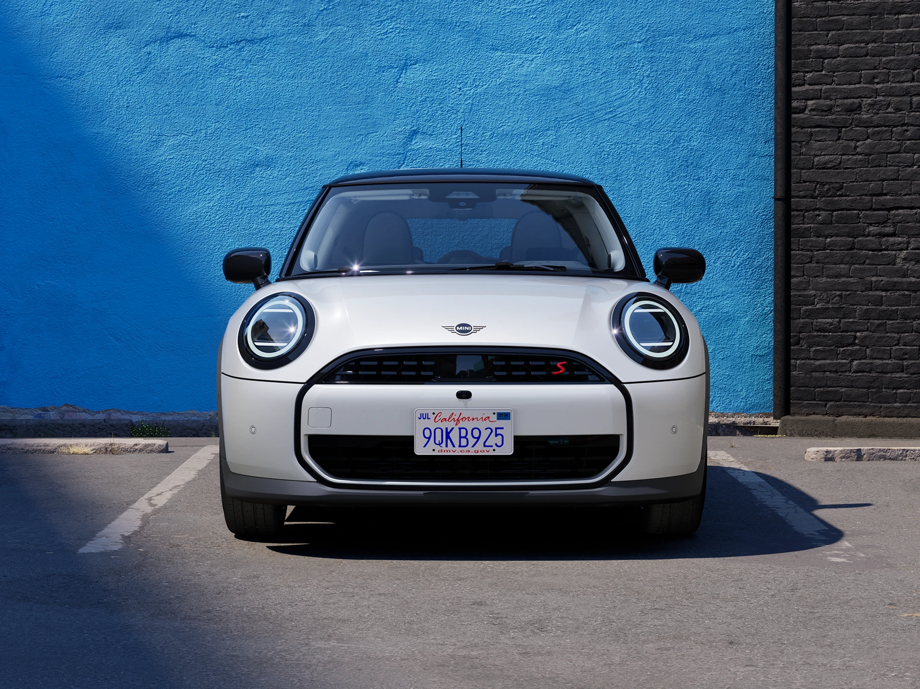 Πλαϊνή όψη του MINI Cooper σε Nanuq White και οροφή σε μαύρο χρώμα, σταθμευμένο.