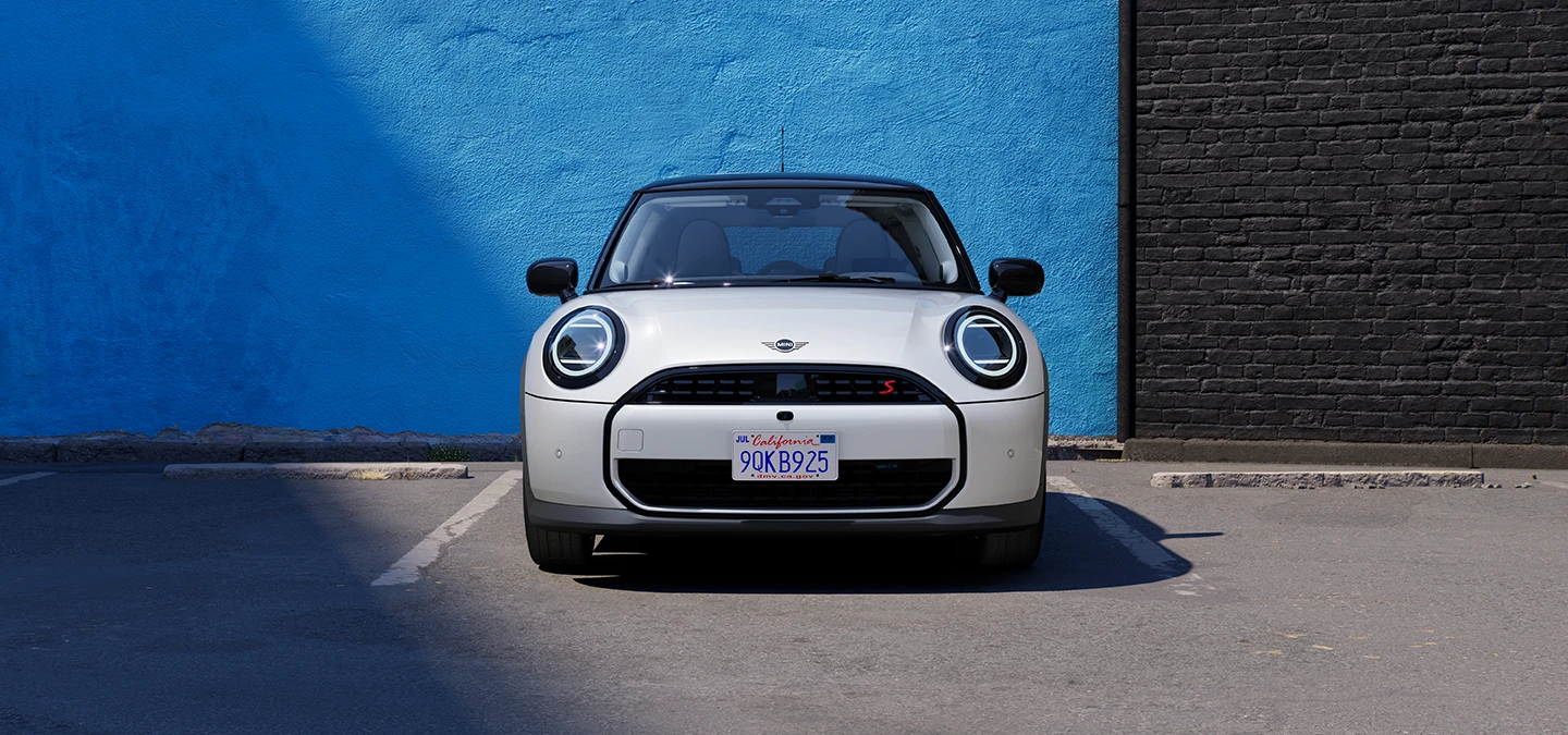 Πλαϊνή όψη του MINI Cooper σε Nanuq White και οροφή σε μαύρο χρώμα, σταθμευμένο.