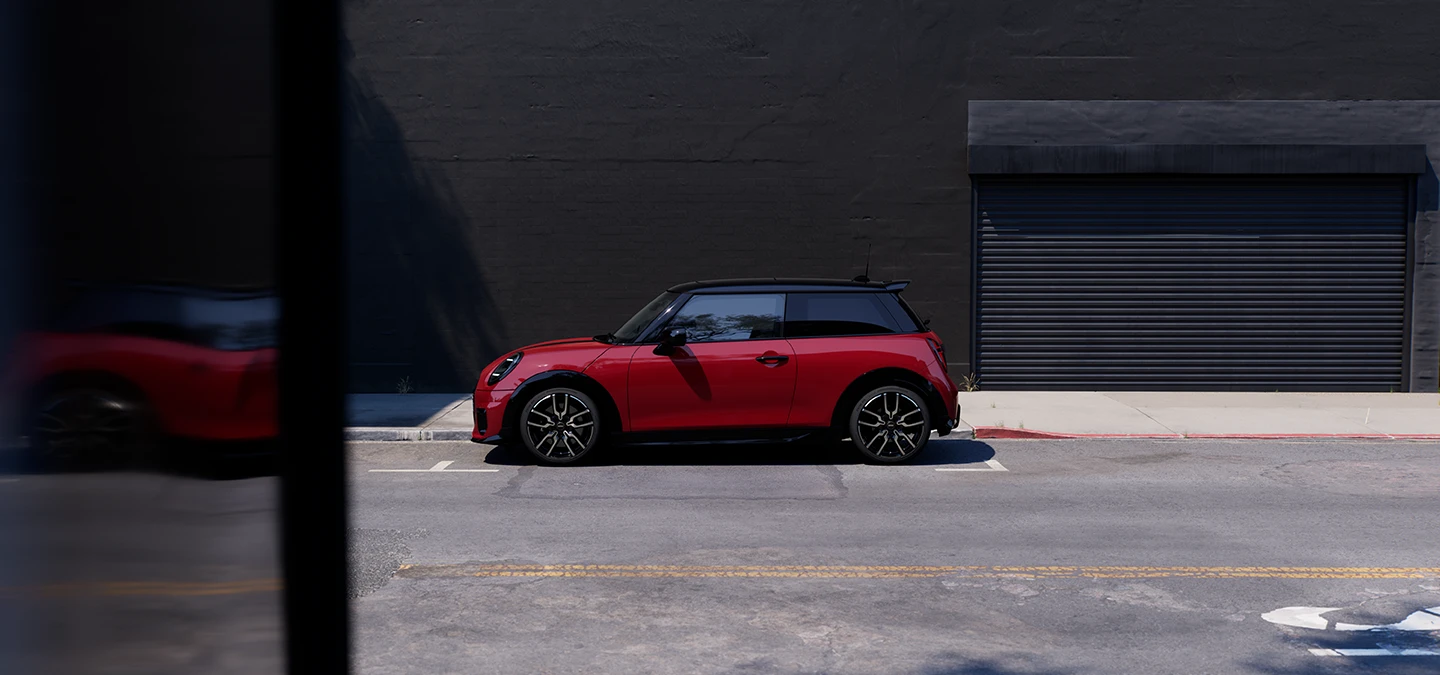 Πλαϊνή όψη του MINI Cooper σε Chili Red και οροφή σε μαύρο χρώμα, σταθμευμένο.