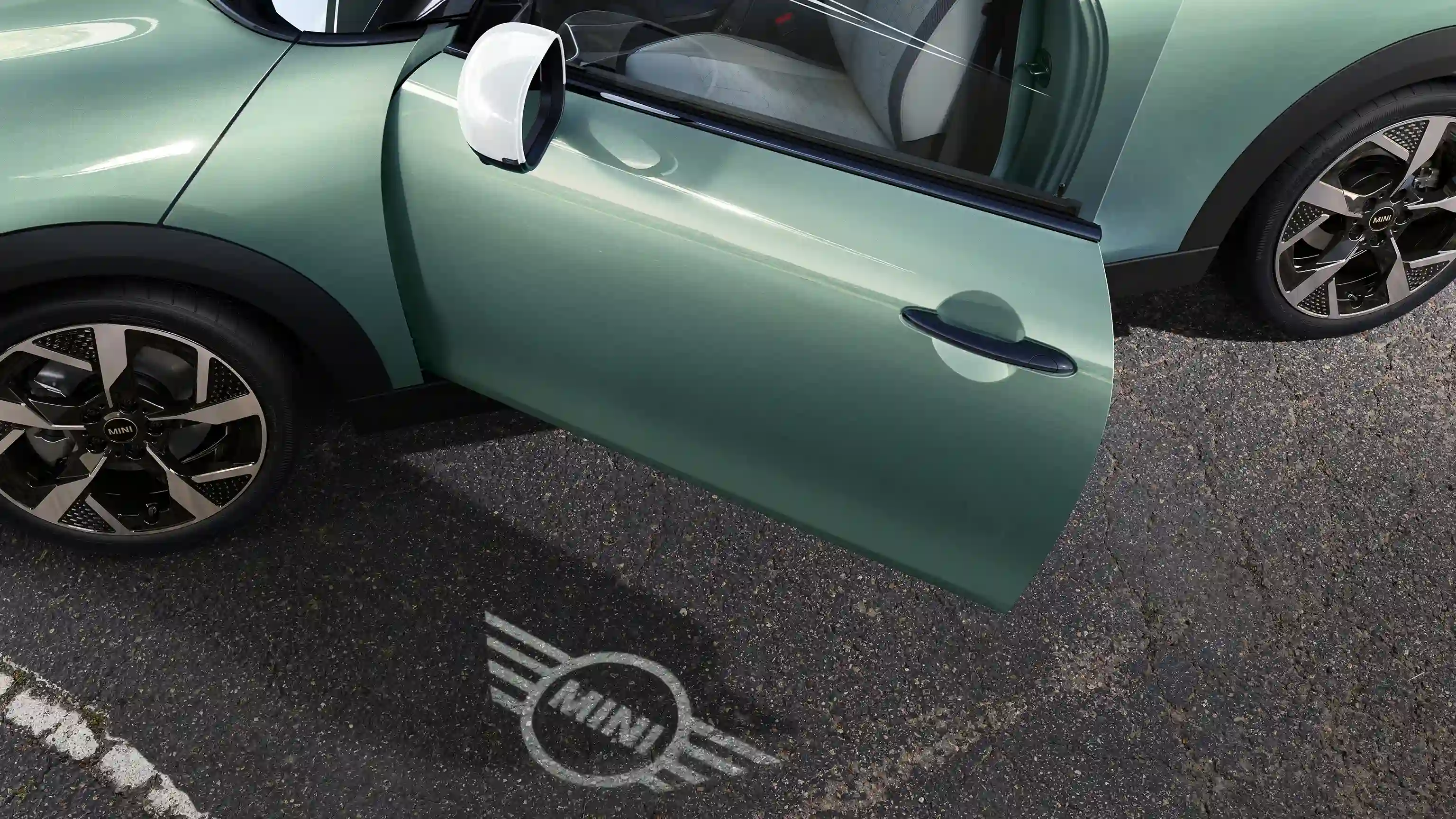Εξωτερική όψη MINI Cooper με ανοιχτή πόρτα και φωτισμό καλωσορίσματος στο έδαφος με λογότυπο MINI