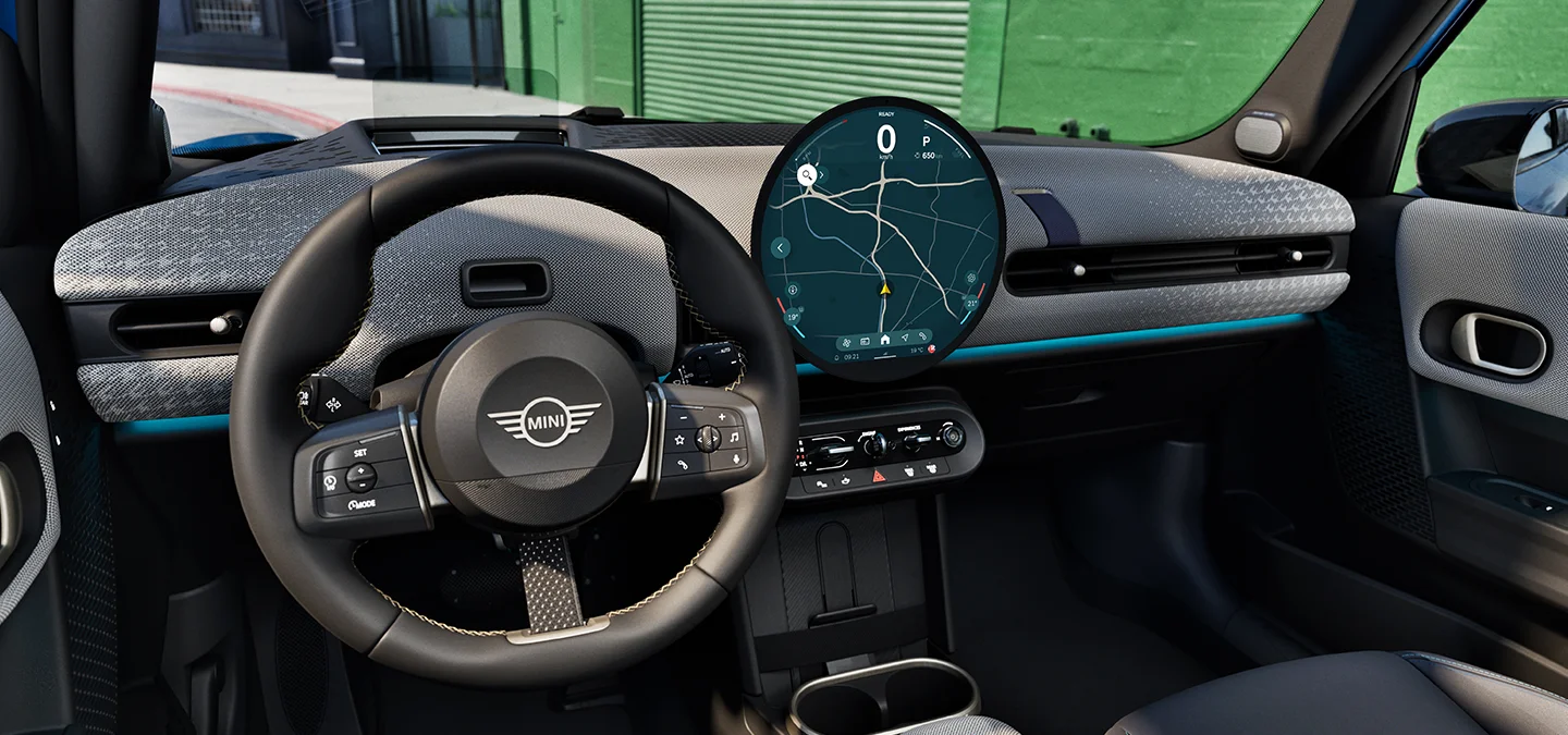 Εσωτερικό του 5θυρου MINI Cooper με εστίαση στο τιμόνι, τον πίνακα οργάνων και τη μονάδα MINI Interaction.