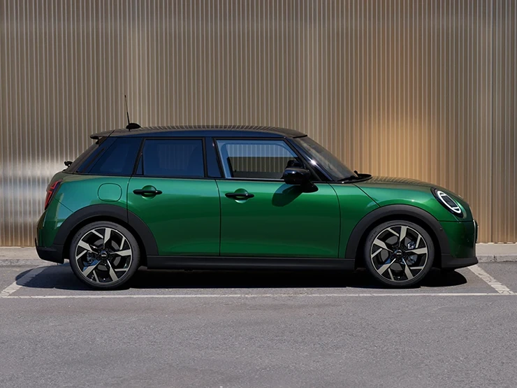 Πλαϊνή όψη του 5θυρου MINI Cooper σε British Racing Green και οροφή σε μαύρο χρώμα, σταθμευμένο.