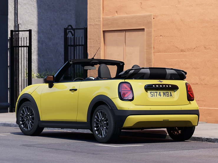 Πίσω αριστερή όψη του MINI Cooper Cabrio σε χρώμα Sunnyside Yellow, σταθμευμένο.