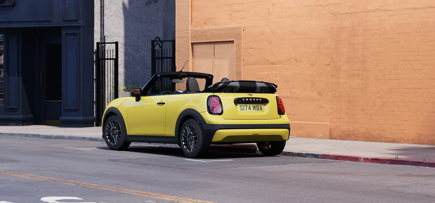 Πίσω αριστερή όψη του MINI Cooper Cabrio σε χρώμα Sunnyside Yellow, σταθμευμένο.