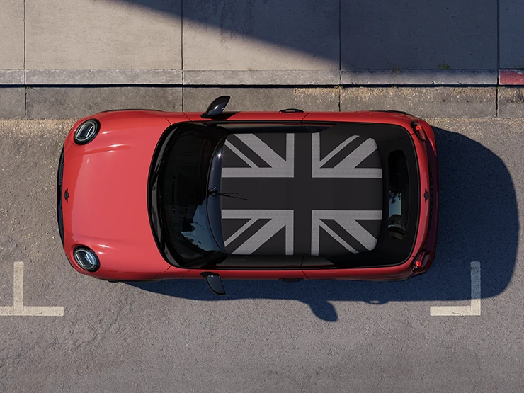 Πανοραμική λήψη του MINI Cooper Cabrio σε χρώμα Chili Red με οροφή MINI Yours, σταθμευμένο σε δρόμο.
