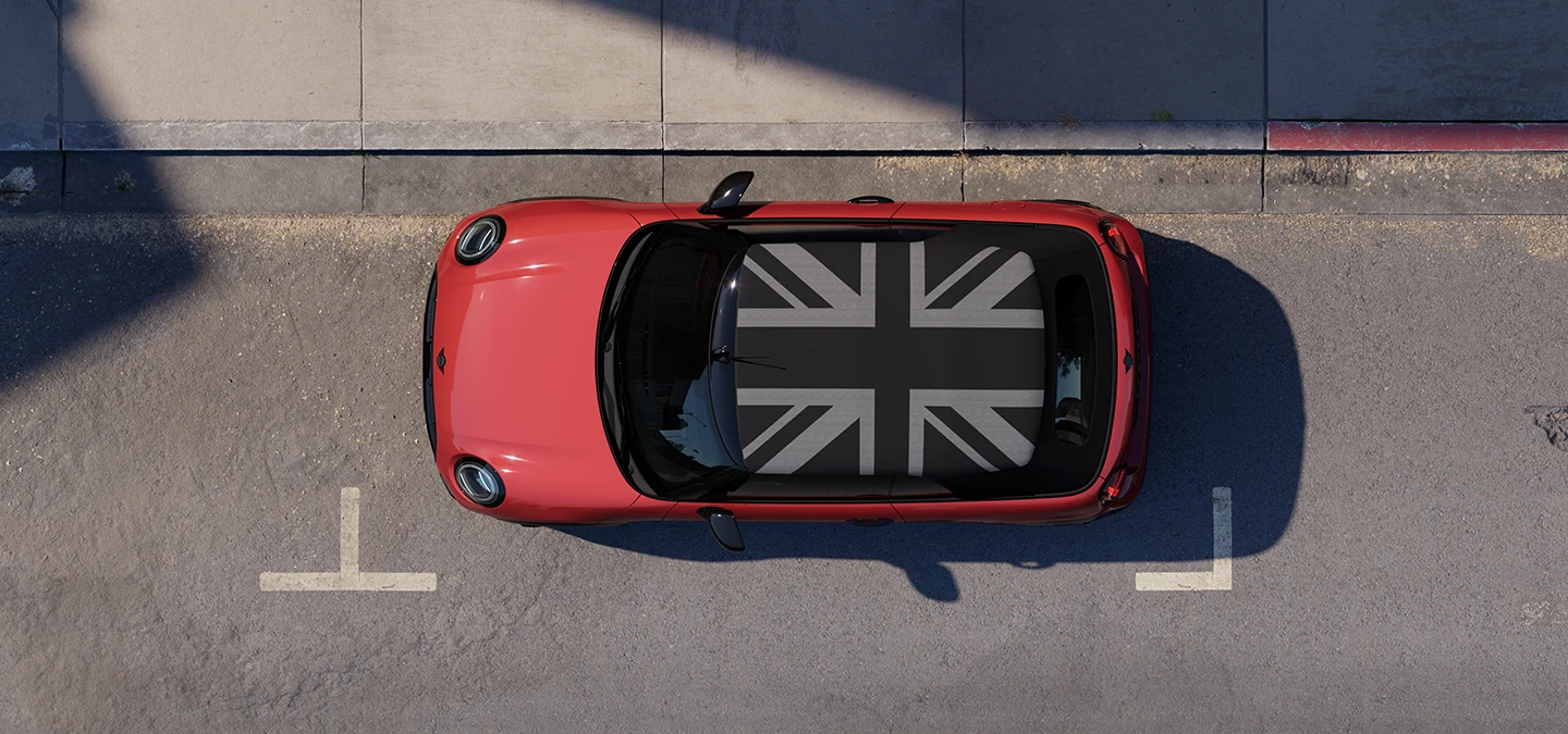 Πανοραμική λήψη του MINI Cooper Cabrio σε χρώμα Chili Red με οροφή MINI Yours, σταθμευμένο σε δρόμο.