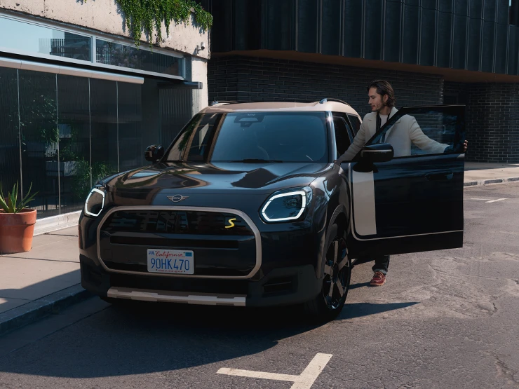 Μπροστινή όψη του αμιγώς ηλεκτρικού MINI Countryman σε χρώμα Midnight Black και οροφή σε χρώμα Vibrant Silver σε δρόμο.