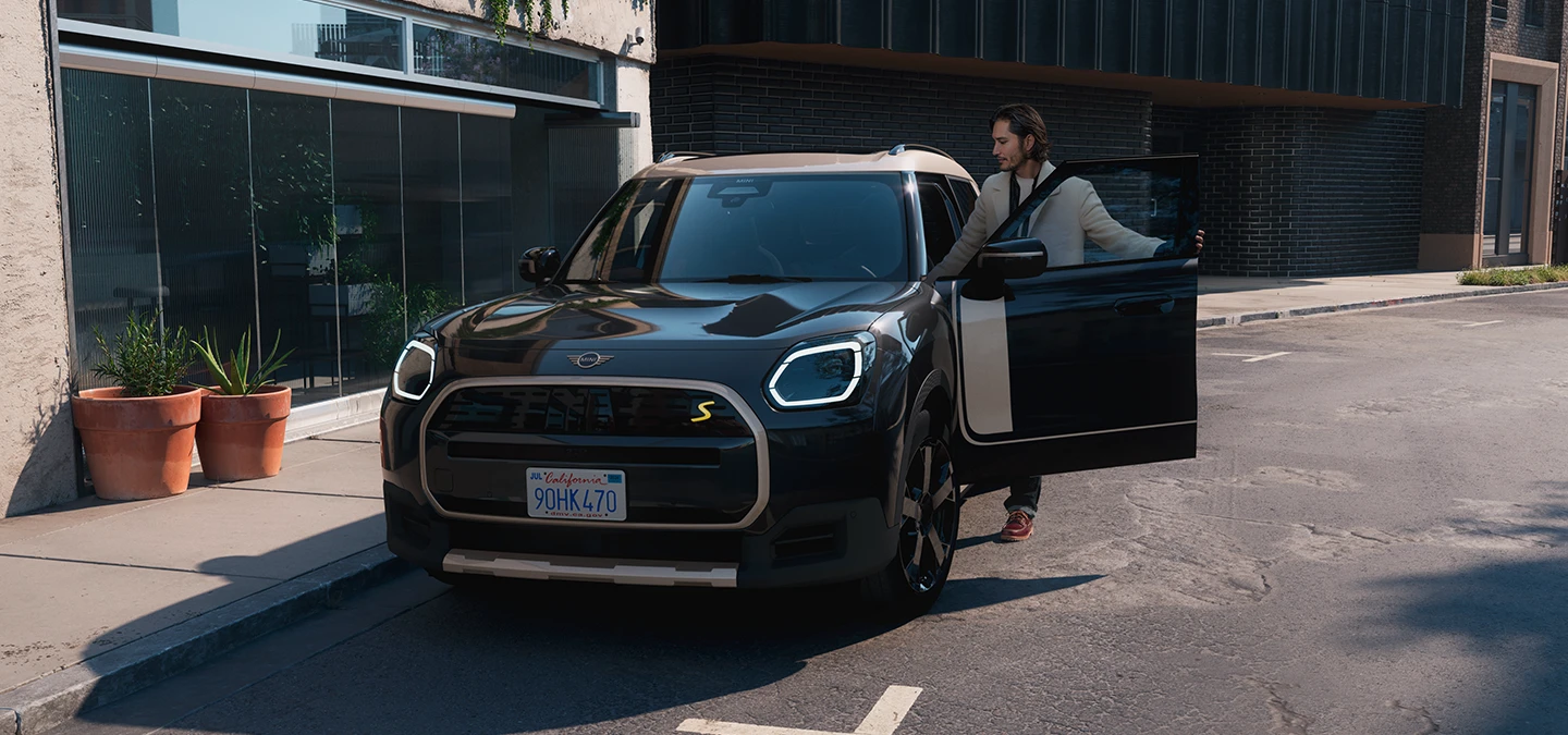 Μπροστινή όψη του αμιγώς ηλεκτρικού MINI Countryman σε χρώμα Midnight Black και οροφή σε χρώμα Vibrant Silver σε δρόμο.