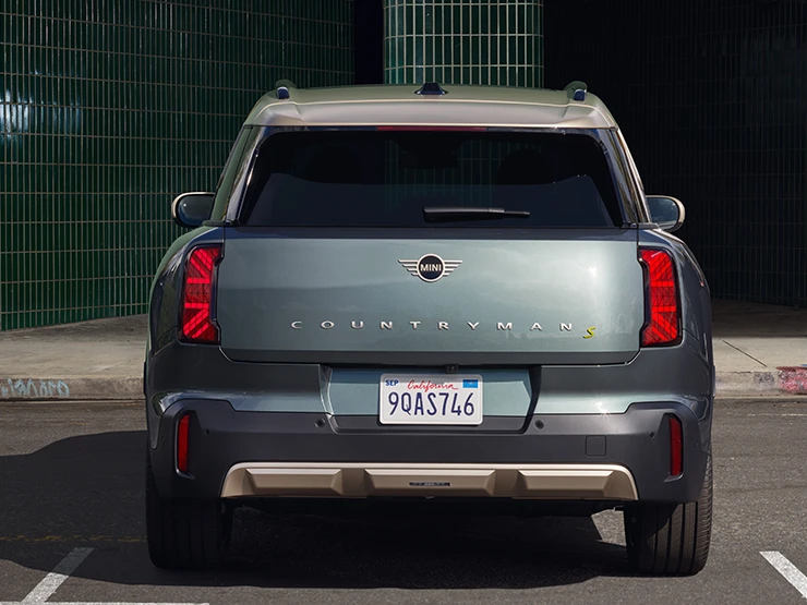Πίσω όψη του αμιγώς ηλεκτρικού MINI Countryman σε χρώμα Smokey Green και οροφή σε χρώμα Vibrant Silver, σταθμευμένο. 