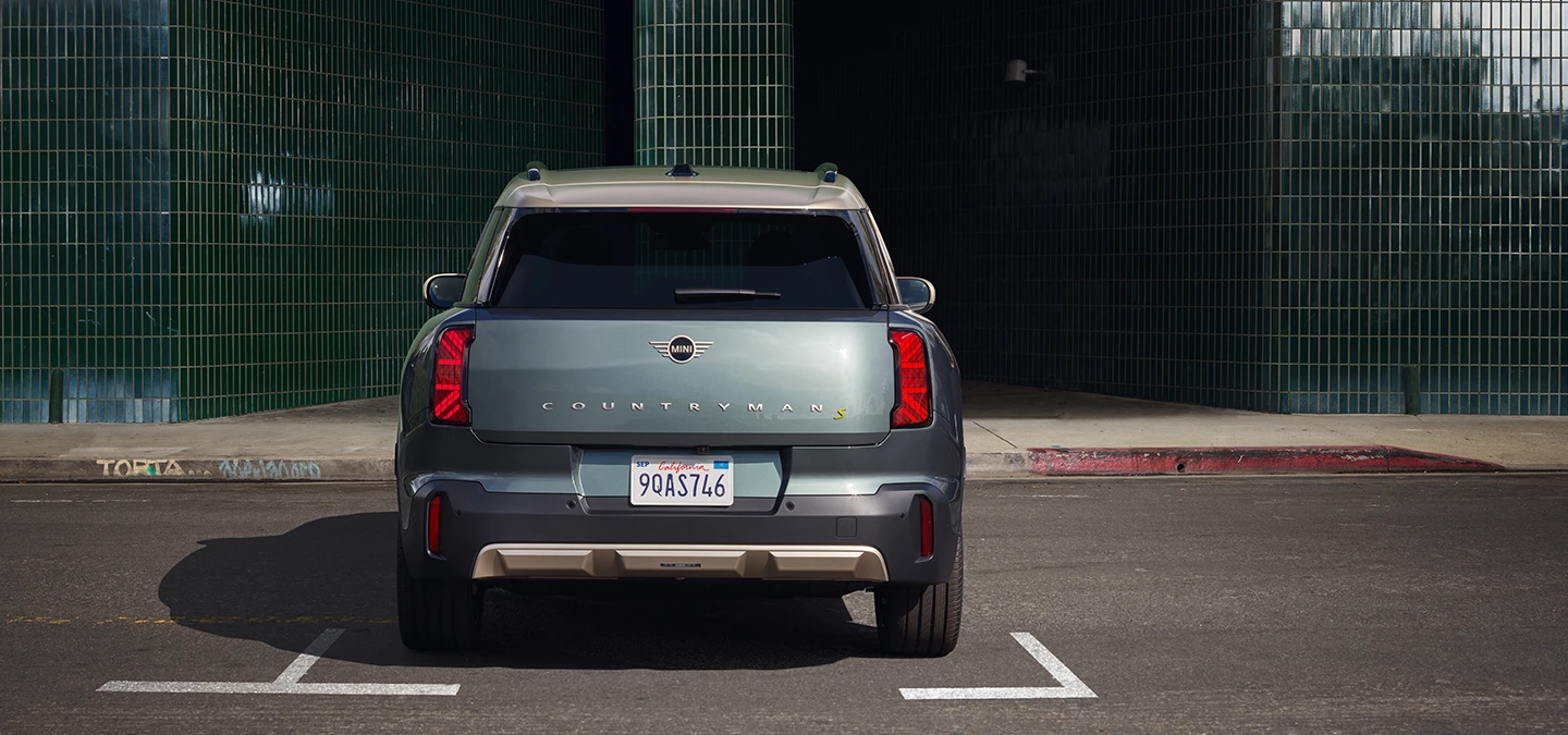 Πίσω όψη του αμιγώς ηλεκτρικού MINI Countryman σε χρώμα Smokey Green και οροφή σε χρώμα Vibrant Silver, σταθμευμένο. 