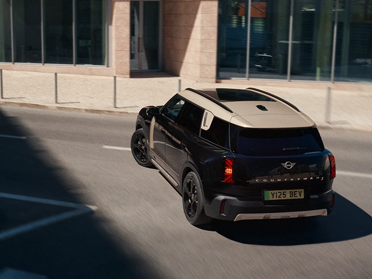 Πίσω όψη του αμιγώς ηλεκτρικού MINI Countryman σε χρώμα Midnight Black και οροφή σε χρώμα Vibrant Silver, σταθμευμένο,