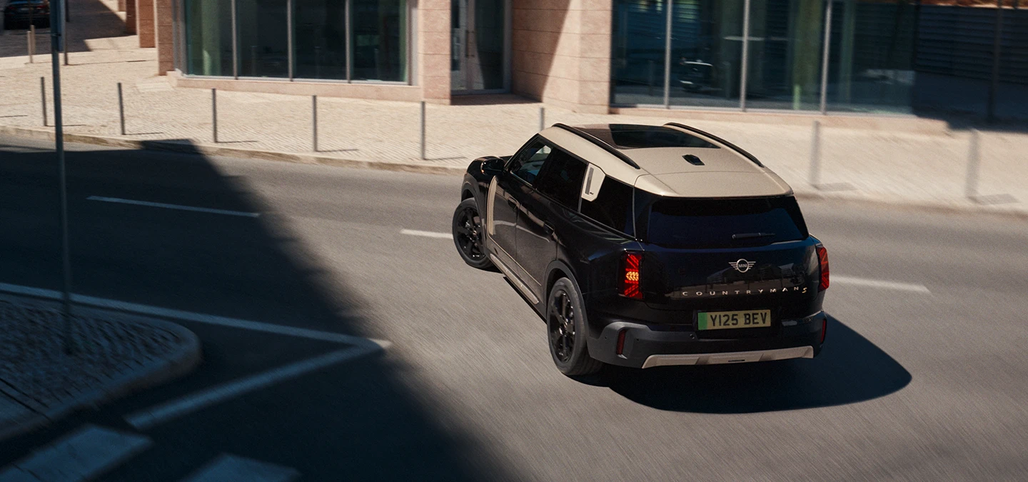Πίσω όψη του αμιγώς ηλεκτρικού MINI Countryman σε χρώμα Midnight Black και οροφή σε χρώμα Vibrant Silver, σταθμευμένο,