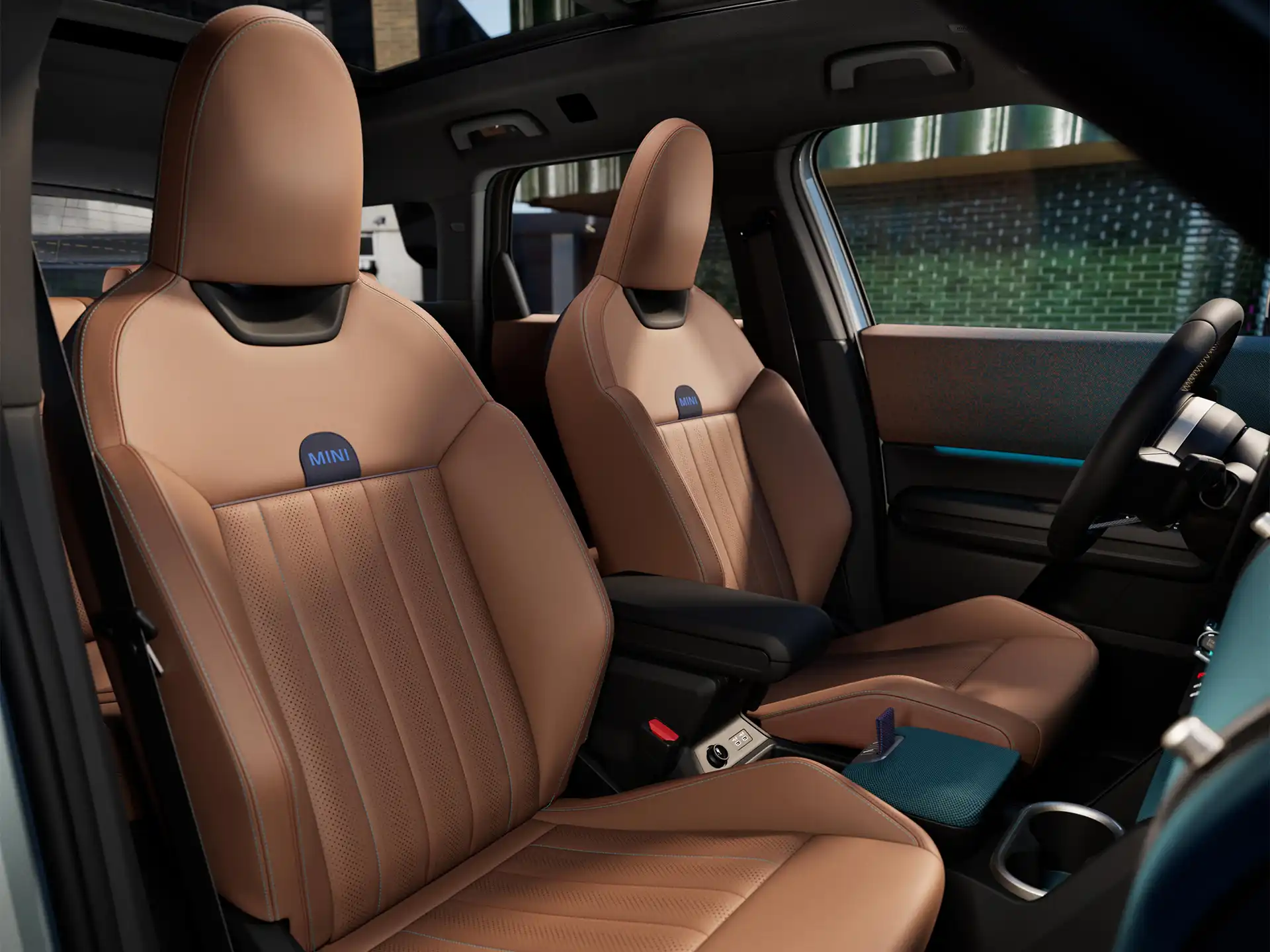 Εσωτερική προοπτική του αμιγώς ηλεκτρικού MINI Countryman που δείχνει το ταμπλό, το τιμόνι, τη στρογγυλή οθόνη, τη γυάλινη πανοραμική οροφή και την πίσω πλευρά των μπροστινών καθισμάτων.