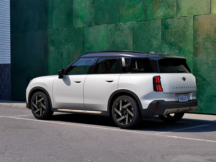 Πλάγια και οπίσθια όψη του MINI Countryman σε χρώμα Nanuq White με μαύρη οροφή, σταθμευμένο σε δρόμο.