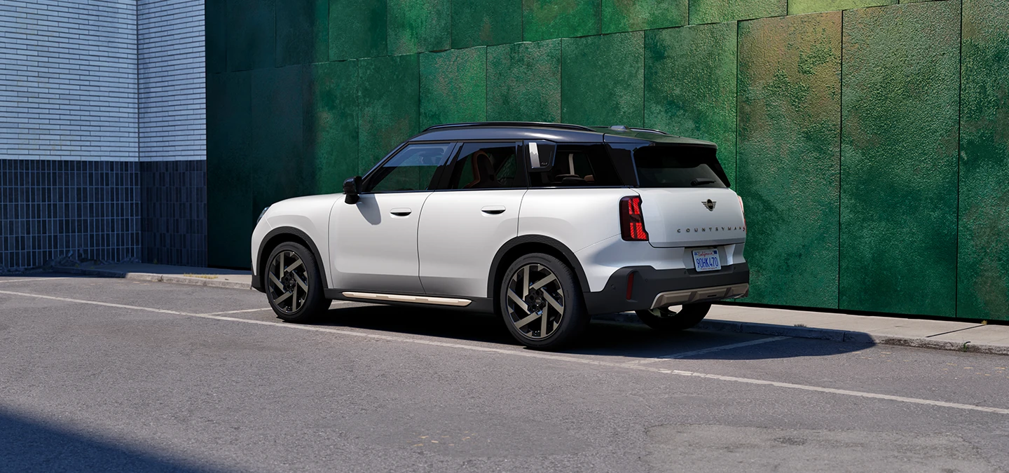 Πλάγια και οπίσθια όψη του MINI Countryman σε χρώμα Nanuq White με μαύρη οροφή, σταθμευμένο σε δρόμο.
