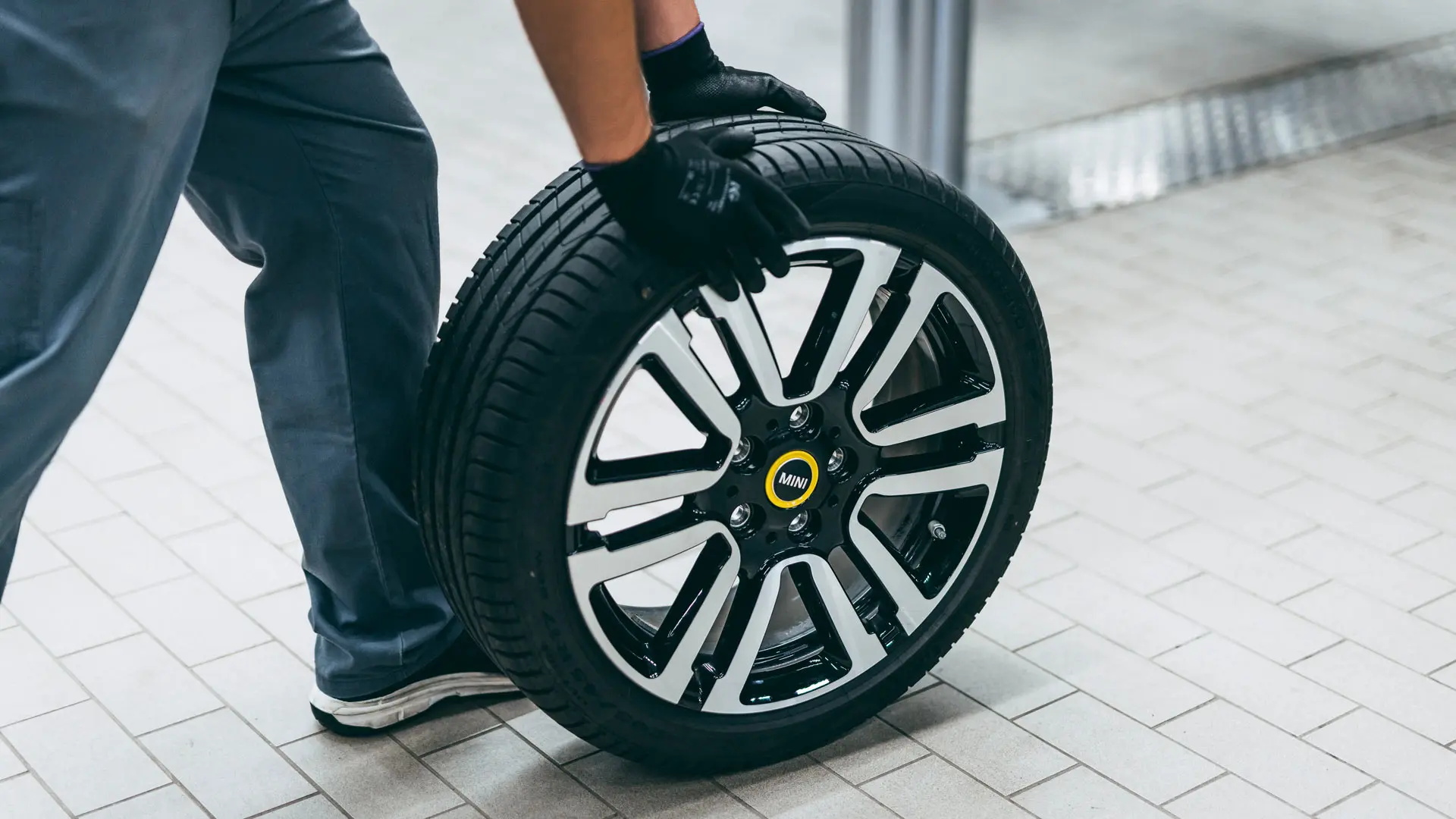 Υπηρεσία Ζαντών και Ελαστικών MINI - τεχνικός MINI κυλά μία ζάντα MINI στις εγκαταστάσεις αποθήκευσης.