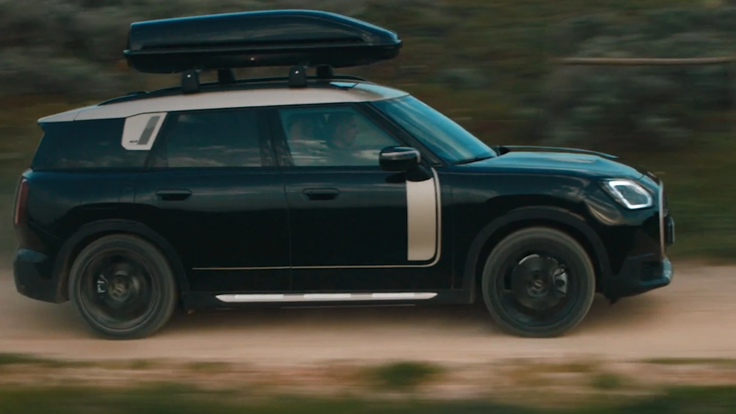 MINI Countryman σε μεταλλικό Midnight Black με τροχούς 19" John Cooper Works Runway Spoke σε μαύρο χρώμα, που κινείται σε έδαφος εκτός δρόμου. 