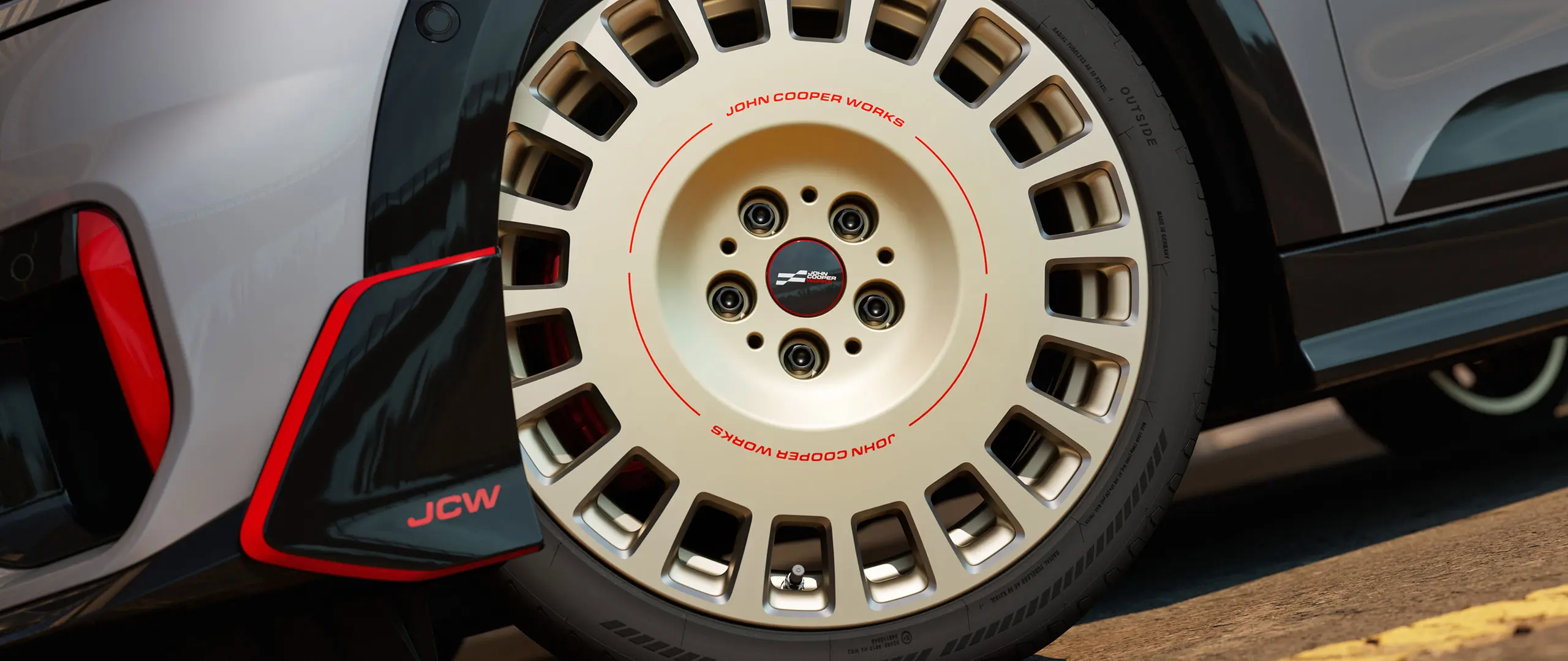 Κοντινό πλάνο των λεπτομερειών της ζάντας 18" JCW Rallye Spoke 964 σε διχρωμία Vibrant Silver, διαμανταρισμένη και μπροστινό winglet.