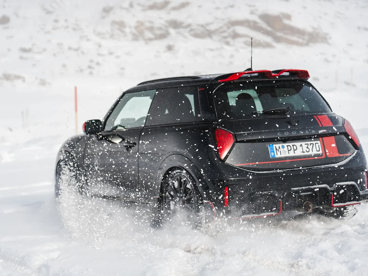Πίσω όψη ενός MINI Cooper JCW κατά την οδήγηση σε χιόνι