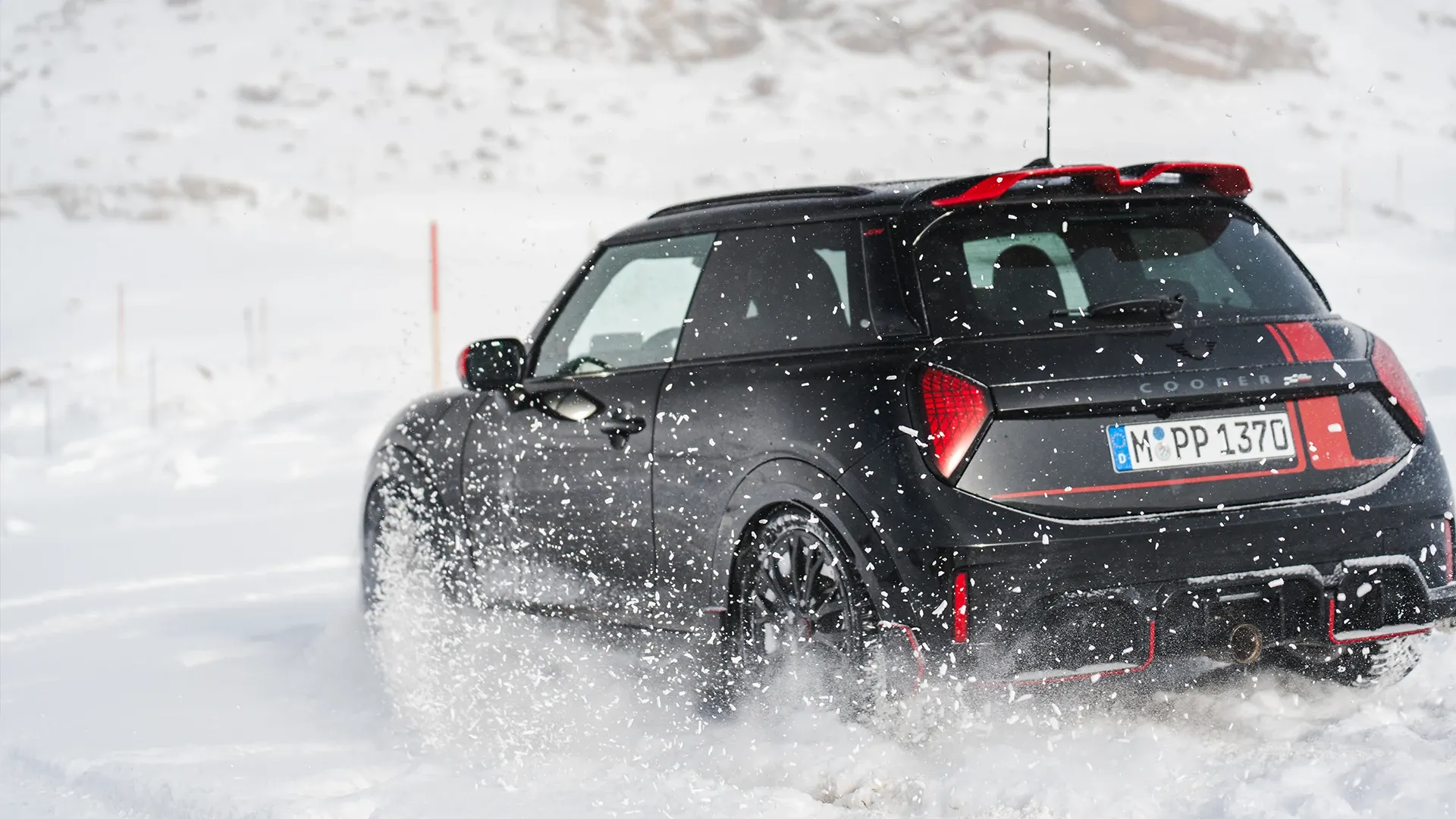 Πίσω όψη ενός MINI Cooper JCW κατά την οδήγηση σε χιόνι