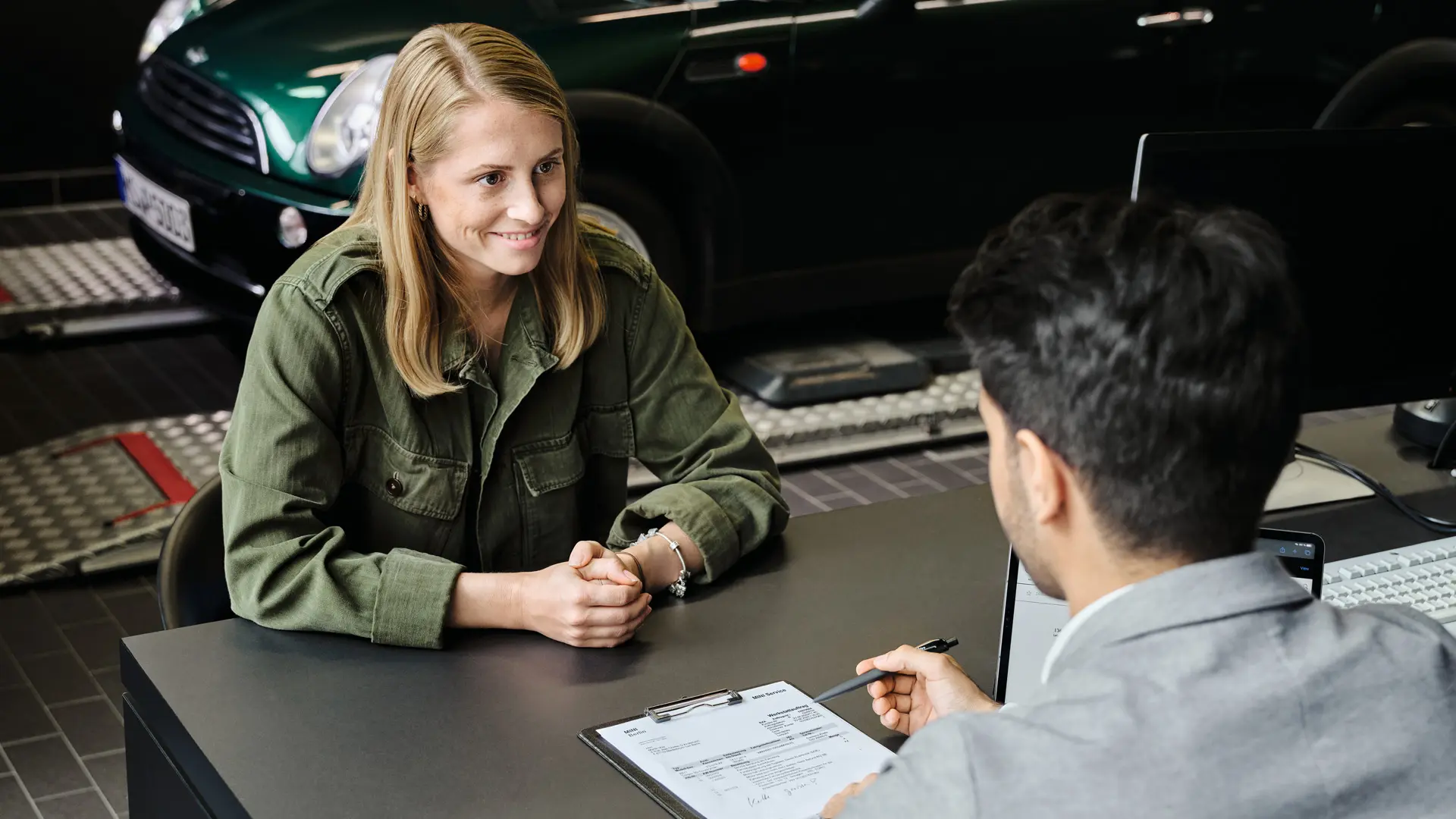 Επίσημος Έμπορος MINI, σύμβουλος συζητά με πελάτη για τις επιλογές service, καθισμένοι και οι δύο σε τραπέζι.