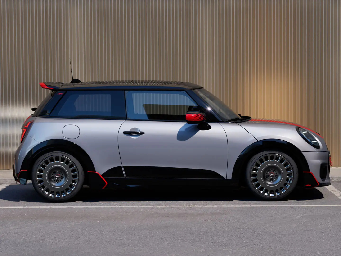 Ένα 3-θυρο MINI Cooper σε Melting Silver με αεροτομή οροφής John Cooper Works για βελτιωμένη αεροδυναμική συμπεριφορά– πλάγια όψη.
