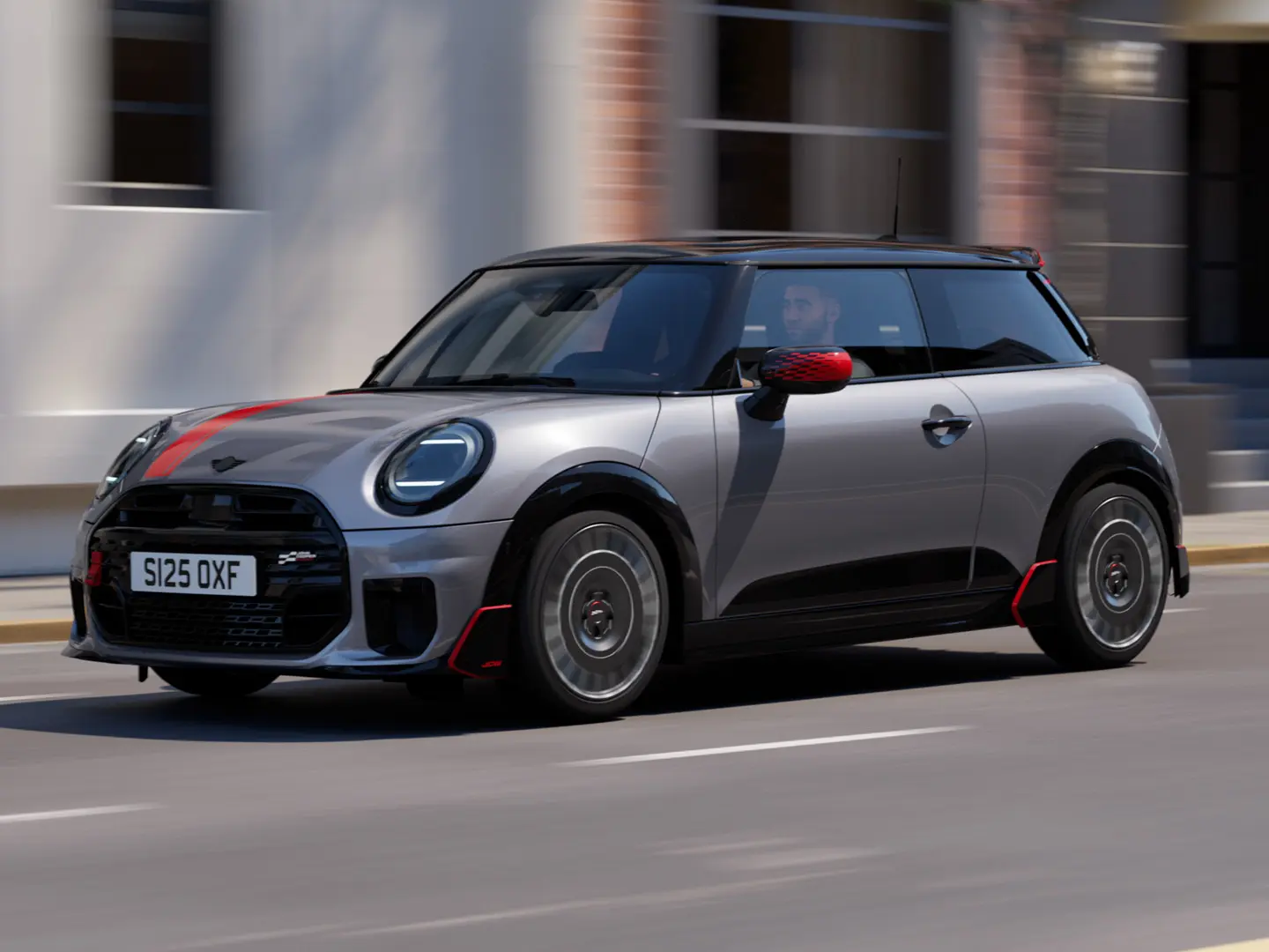 Ένα 3-θυρο MINI Cooper σε Melting Silver με καλύμματα εξωτερικών καθρεπτών John Cooper Works και αυτοκόλλητο στο καπό του κινητήρα σε Chili Red, αεροτομή οροφής και πτερύγια αεροτομής σε μαύρο χρώμα κινείται σε έναν αστικό δρόμο – μπροστινή όψη από το πλάι.