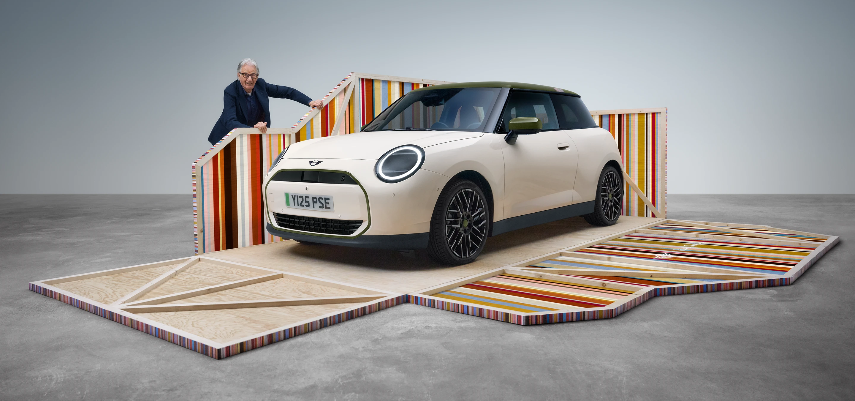 Μπροστινή λήψη του αμιγώς ηλεκτρικού MINI Cooper Paul Smith Edition σε Inspired White με τον σχεδιαστή Paul Smith
